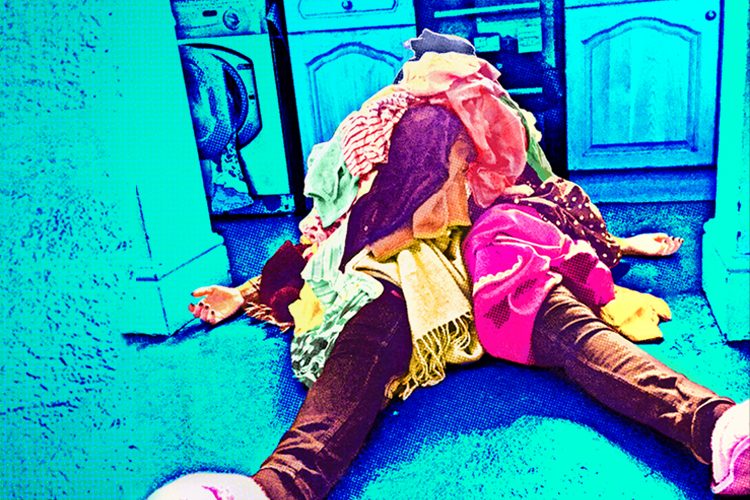 over saturated photo of a person lying on the floor of a kitchen with a heap of clothes on top of them